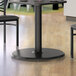 A Lancaster Table & Seating black round table base with a wood grained surface.