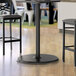A Lancaster Table & Seating black round bar height table with a black column base.
