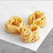 Several pieces of Barilla Egg Fettuccine Pasta on a white surface.