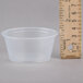 A clear Dart plastic souffle cup next to a ruler.