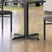 A black metal Lancaster Table & Seating table base with a table and chairs on it.