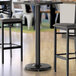 A Lancaster Table & Seating black bar height table base with two chairs.