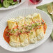 A white plate with Barilla Manicotti pasta, sauce, and sprouts.