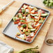 A Wilton non-stick baking sheet with brussels sprouts and carrots on it.