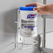 A hand using a white wall bracket to hold a container of Purell disinfectant wipes.
