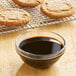 A bowl of molasses next to cookies.