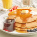 A plate of pancakes with Maple Grove Pancake Syrup and fruit.