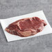 A piece of raw TenderBison ribeye steak on white paper.