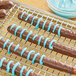 Chocolate covered pretzels coated in Alpine blue vanilla coating on a cooling rack.