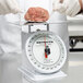 A person weighing a piece of meat on a Cardinal Detecto portion scale.
