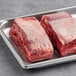 Two pieces of raw bone-in bison short ribs in a metal tray.