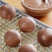 Milk chocolate covered balls on a metal cooling rack.