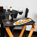 A Cambro non-skid serving tray on a table with food and wine.