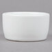 A Tuxton white smooth china ramekin on a gray table.
