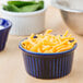 A close-up of a blue CAC China fluted ramekin filled with cheese.