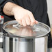 A person holding a Vollrath Optio lid over a pot.