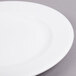 An Arcoroc white porcelain plate with a white rim on a gray surface.