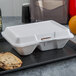 A white styrofoam takeout container with two compartments of food and a cookie.