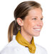 A woman wearing a gold chef neckerchief with a yellow tie around her neck.