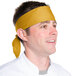 A man wearing a gold chef neckerchief on his head.