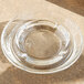 A Libbey clear glass ashtray on a wood surface.