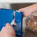 A person using a Shurtape poly bag sealer to package bread in a plastic bag.