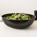 A black Cambro Camwear round ribbed bowl filled with salad on a white surface.