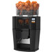 A black Zummo Z14 commercial juicer with oranges in it.