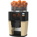 A Zummo Z14 commercial juicer with a basket of oranges inside.