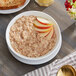 A bowl of Bob's Red Mill apple cinnamon oatmeal with sliced apples on top.