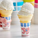A close-up of a white JOY flat bottom jacketed cake cone filled with ice cream and sprinkles.