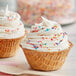 A JOY waffle cone bowl filled with white frosting and sprinkles.