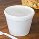 A white plastic container with a white Dart lid and a white spoon.
