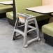A Rubbermaid restaurant high chair with wheels at a table.