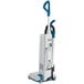 A white and blue Makita upright vacuum cleaner with a handle.