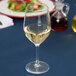 A Stolzle white wine glass filled with white wine on a table.