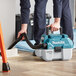A person using a Makita wet/dry vacuum to clean a floor.