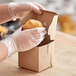 A person in gloves putting a muffin in a Baker's Mark kraft cupcake box.