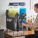 A woman pouring a blue drink into a Bunn Ultra NX slushy machine.