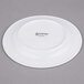 A white porcelain side plate with black Arcoroc text.