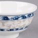 A close up of a blue and white Thunder Group Blue Dragon melamine rice bowl.