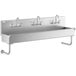 A Regency stainless steel multi-station hand sink with wall mounted faucets.