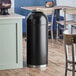 A Lancaster Table & Seating black steel decorative waste receptacle with open dome lid.