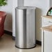 A Lancaster Table & Seating stainless steel trash can in a corner.