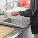 A hand using a white Choice polypropylene bus tub to wash dishes in a sink.