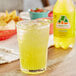 A glass of Jarritos pineapple soda on a table next to a bottle of Jarritos pineapple soda.