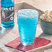 A glass of Jones Blue Bubblegum Soda with popcorn and a bottle on a tray.