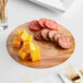 An Enjay reversible charcuterie board with cheese and sausage on it.