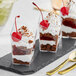 Three clear plastic containers filled with chocolate and cherry desserts.