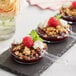 Three clear plastic mini frying pans with raspberry and oatmeal crumble desserts.